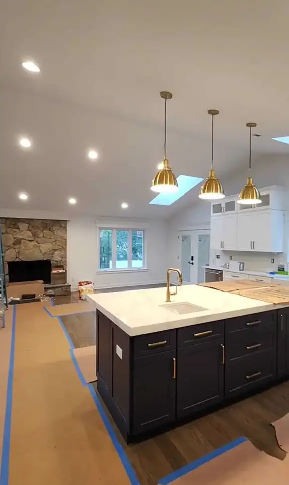 Modern kitchen renovation with recessed lights and gold pendant fixtures
