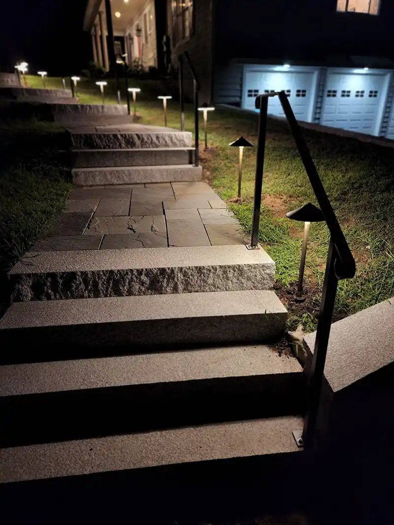 Stone pathway with pathway lights leading to home at night