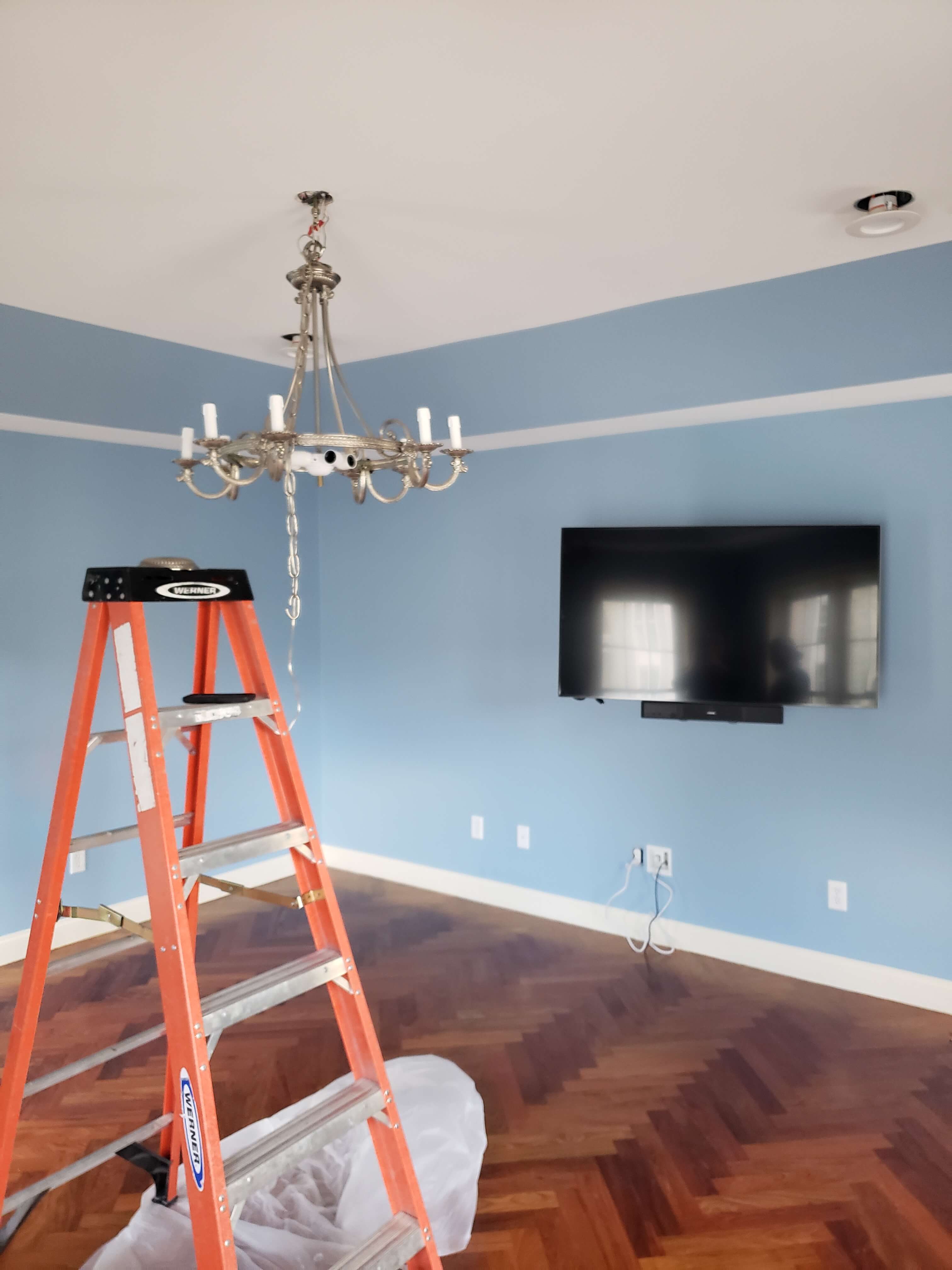 Chandelier installation in blue room with TV mount