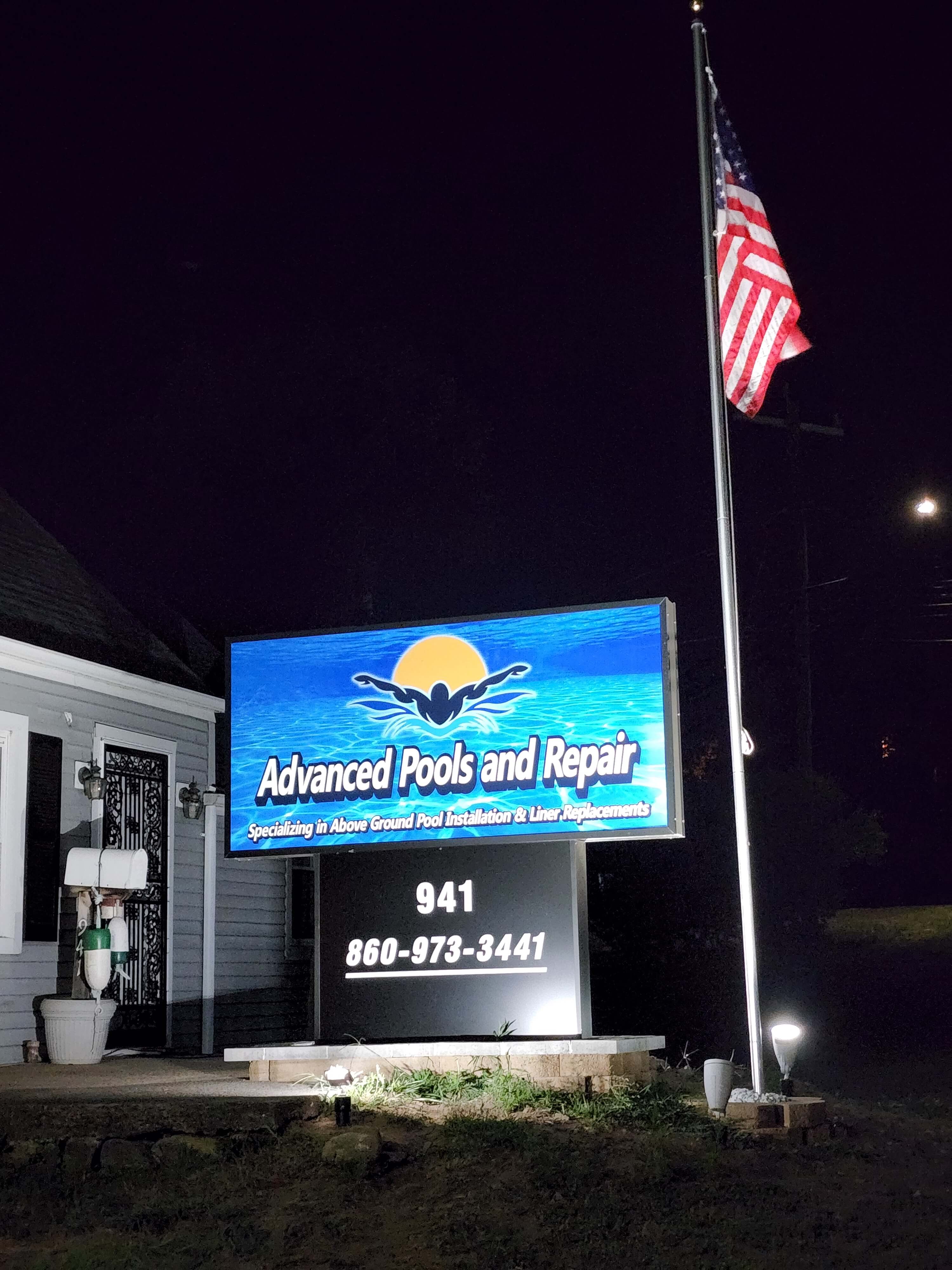 Illuminated commercial business sign with flag lighting at night