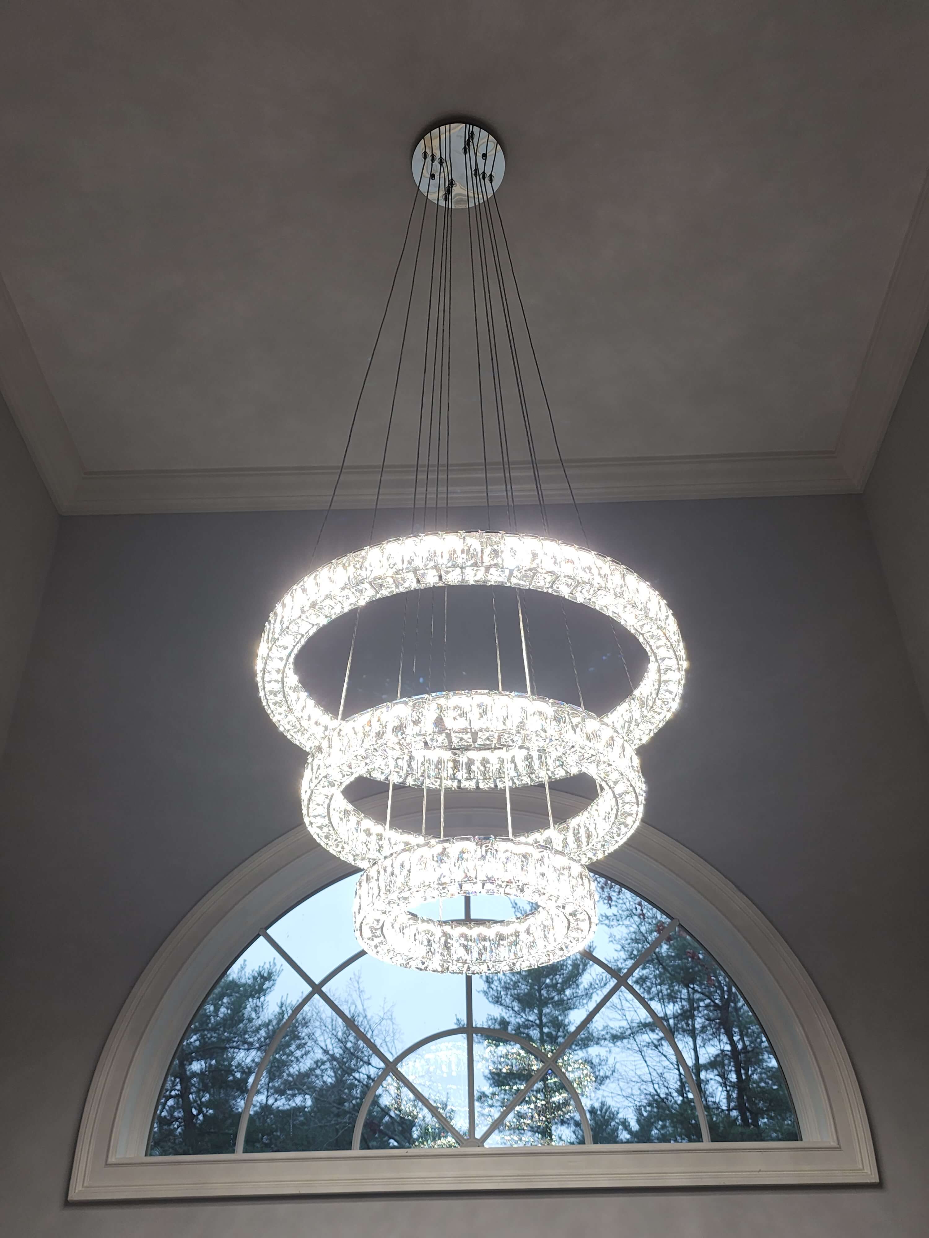 Three-tier crystal ring chandelier in foyer with arched window