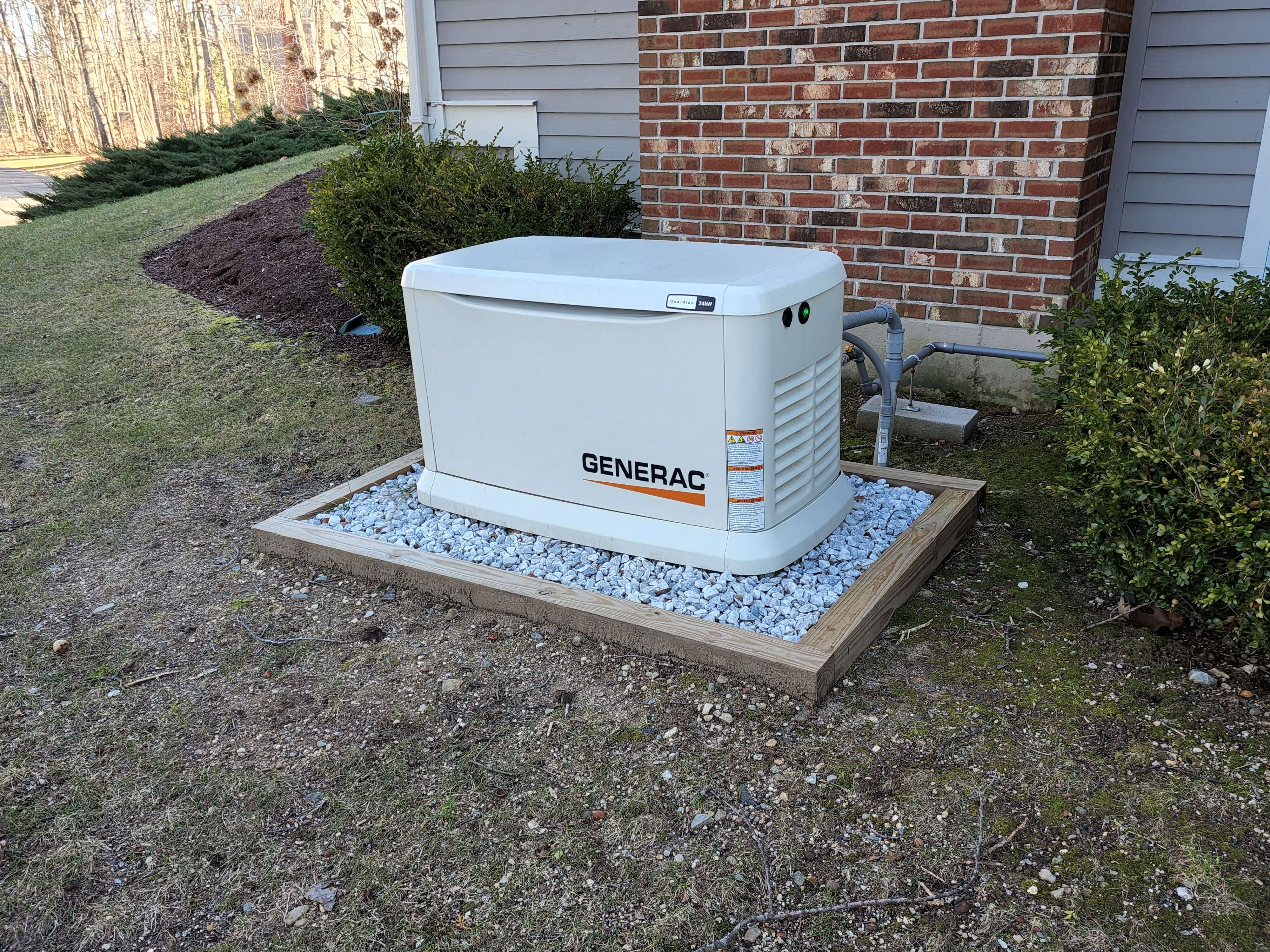 Generac generator on white gravel pad next to brick home