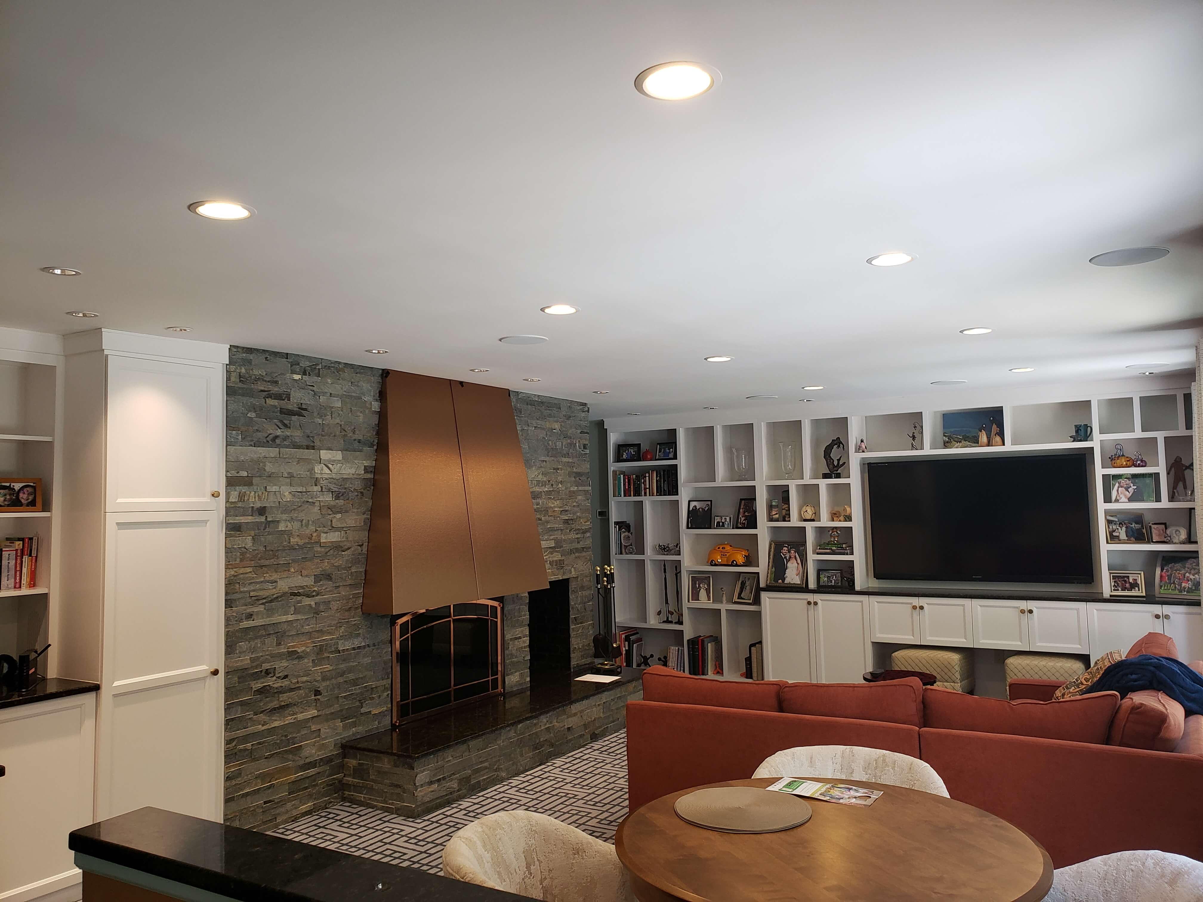 Living room with stone fireplace, copper hood, and recessed lighting