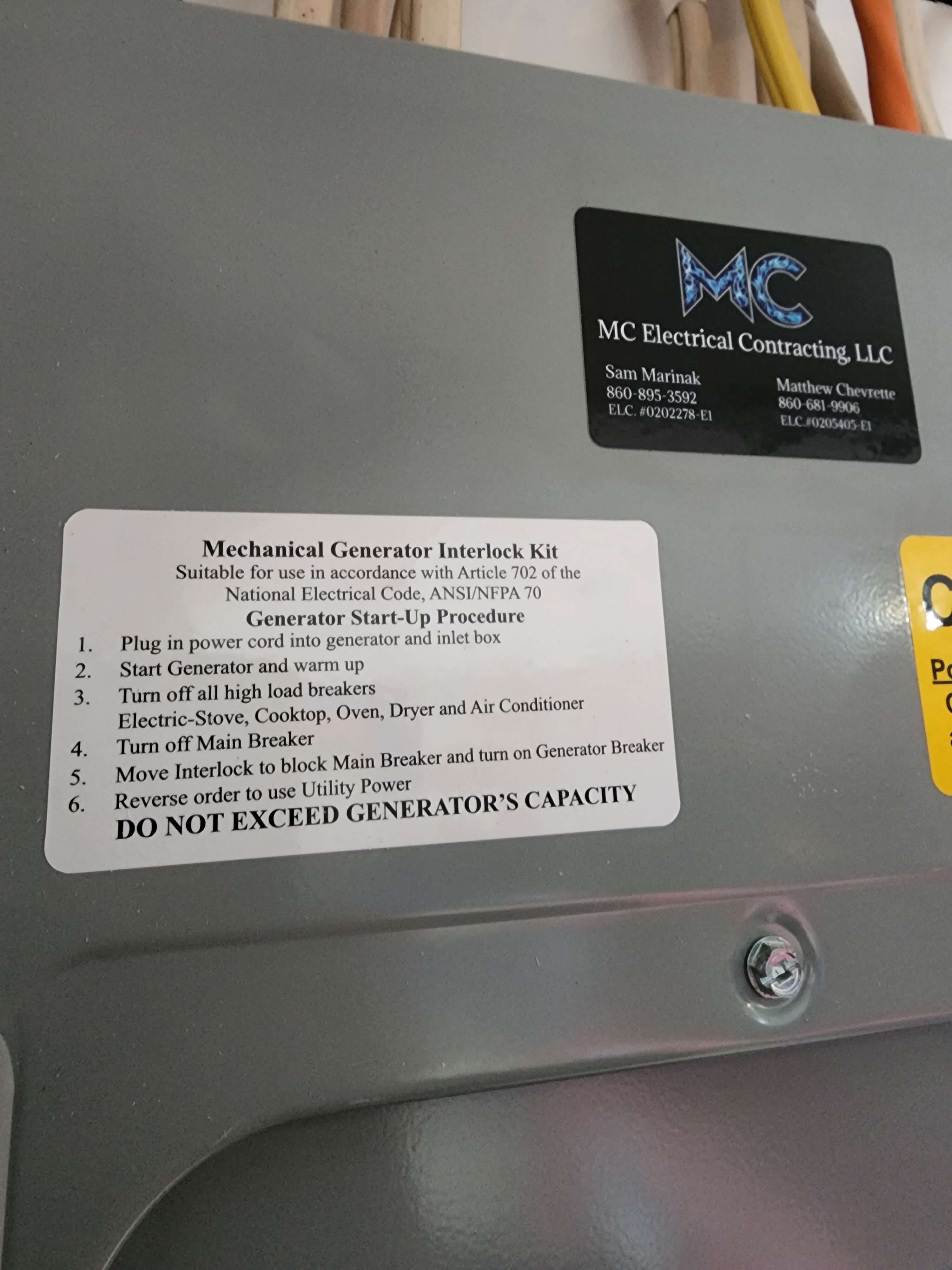 Electrical panel with MC Electrical business card and interlock instructions