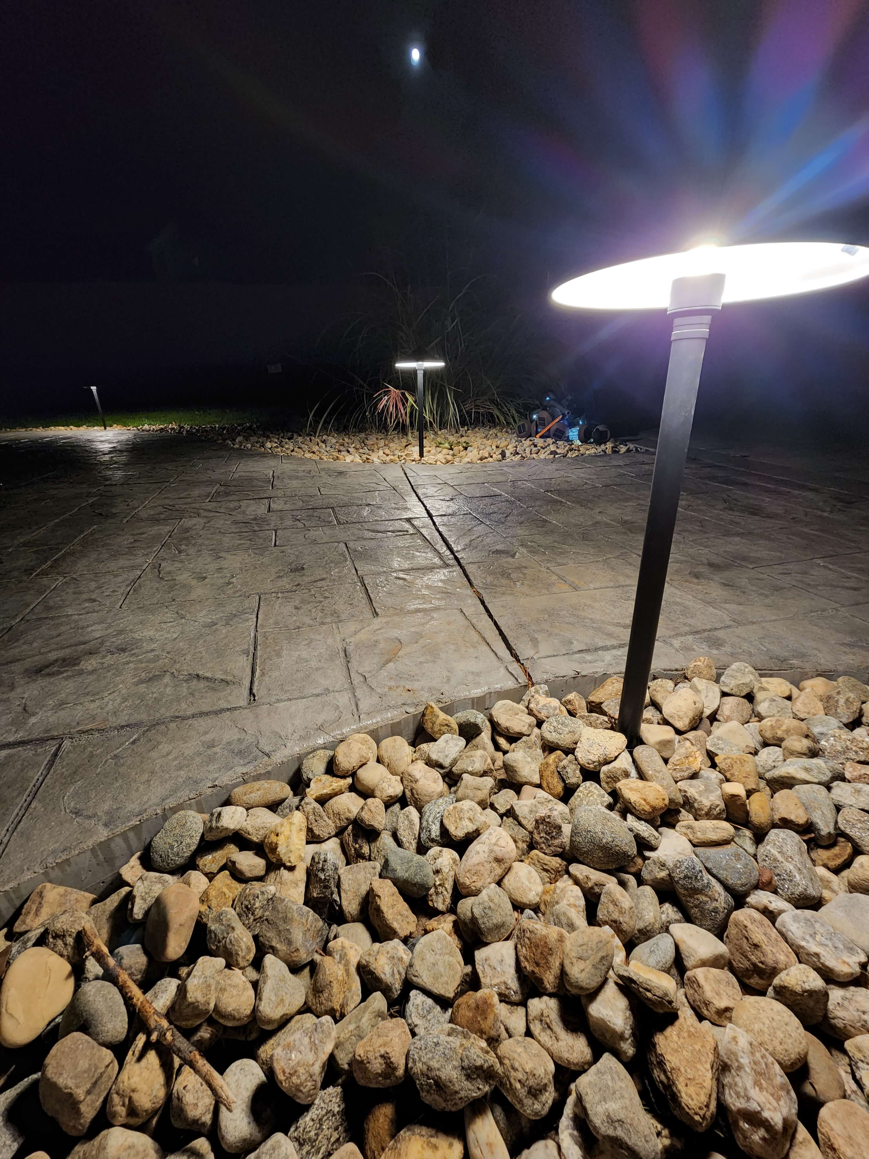 Close-up of modern mushroom style pathway light on patio with rock border