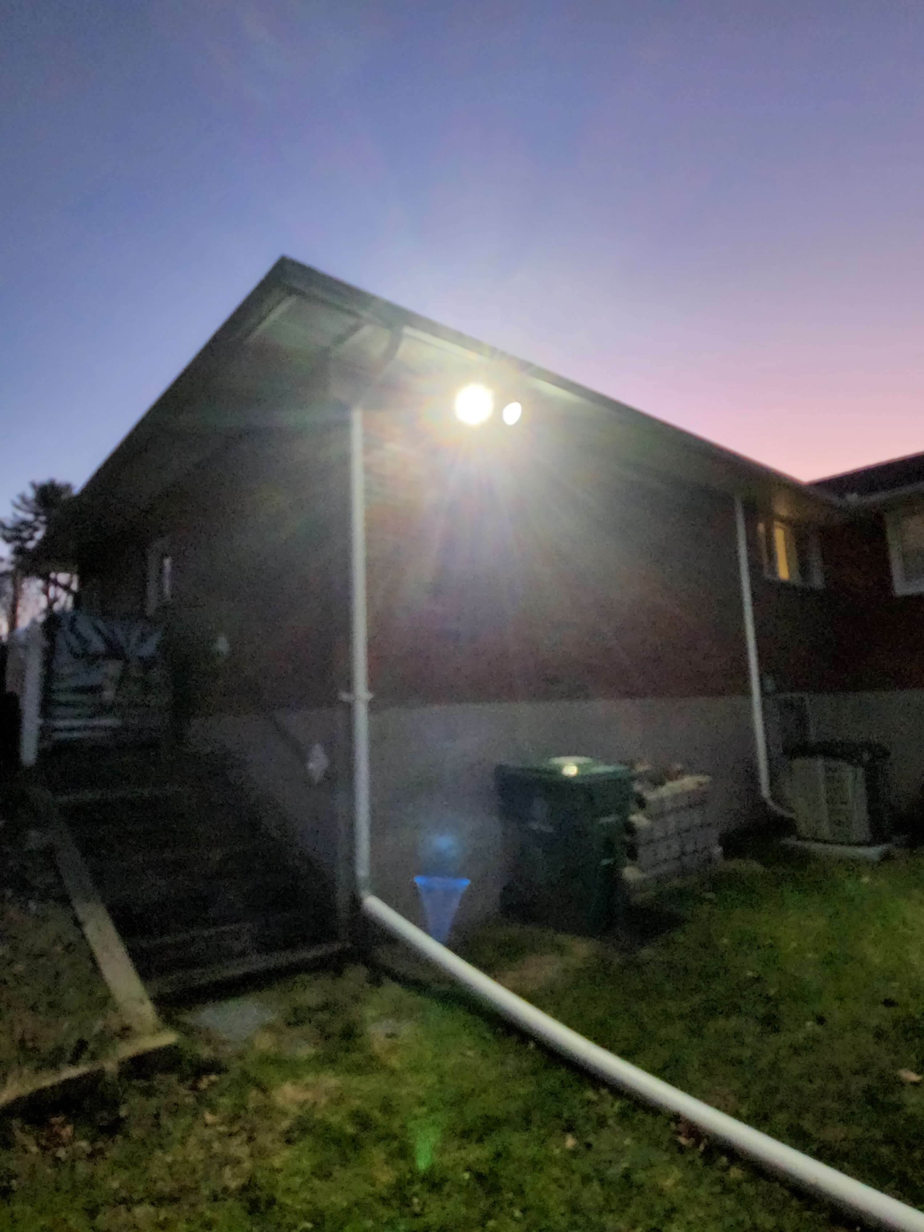 Outdoor shed illuminated by security flood light at dusk