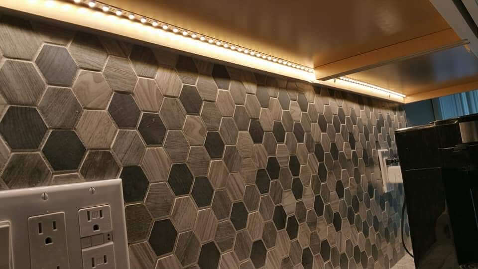 LED strip lighting under kitchen cabinets with hexagonal tile backsplash
